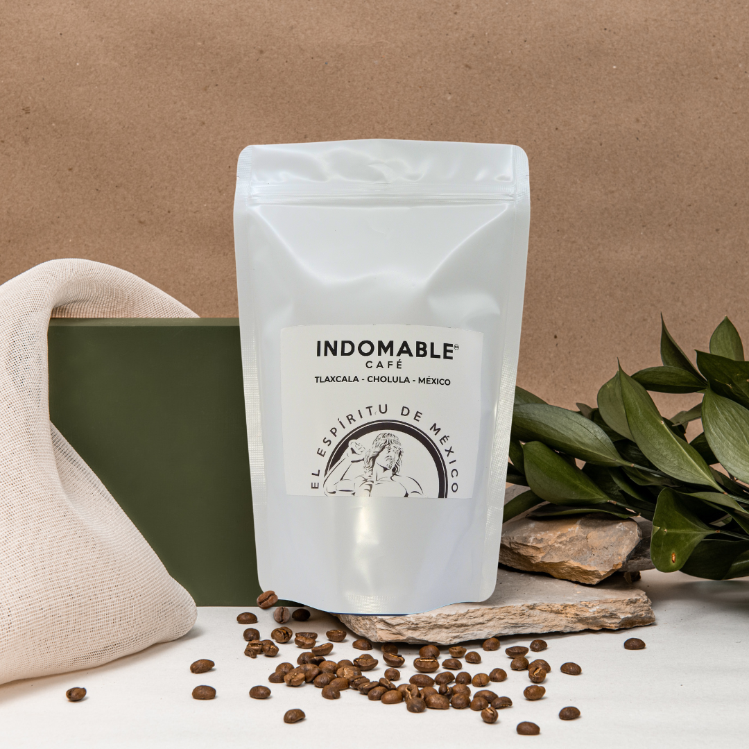 Café Auténtico 500g - Indomable Café | Sabor Único en empaque blanco con logotipo, junto a granos y café molido sobre fondo rústico.